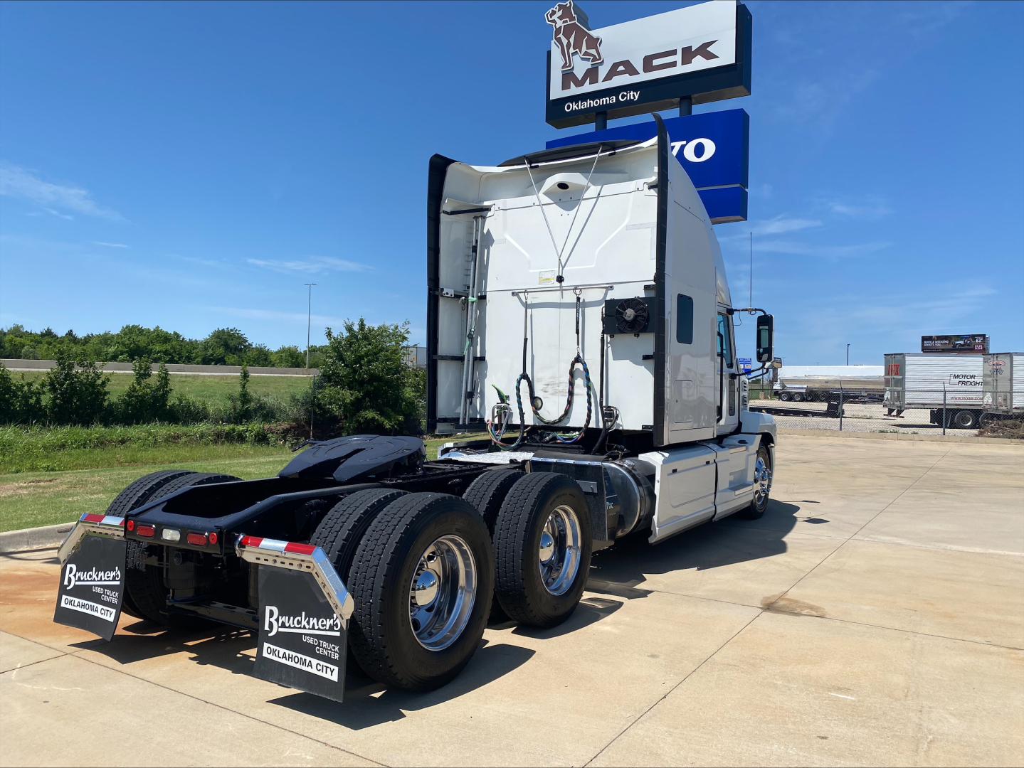 Mack AN64T70 conventional sleeper truck rear view showing cab, dual rear axles, and fenders with dealership mudflaps and Bracken Trucking logo