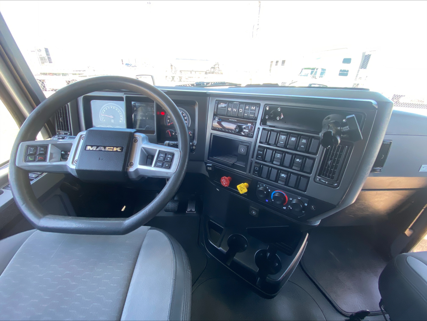 Mack AN64T70 truck cab interior showing steering wheel, dashboard with gauges, control buttons, and gear shifter.