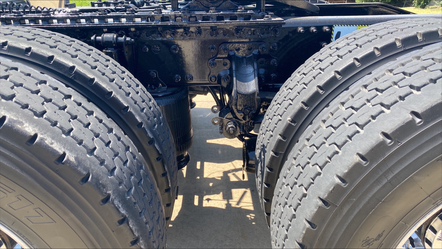 Mack AN64T70 truck rear wheels and drivetrain seen from between tandem axles, showing suspension and drive components.