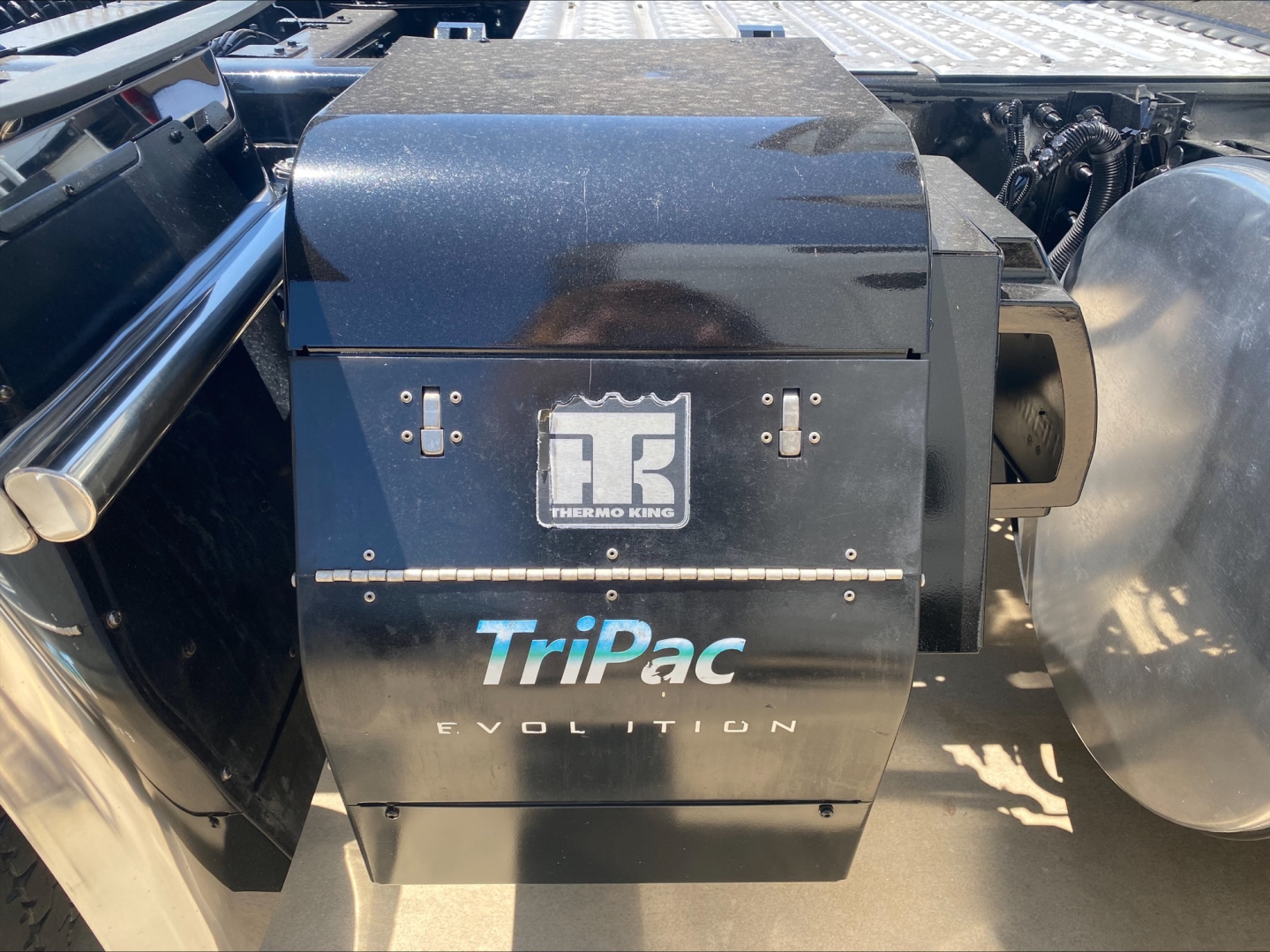 Truck cab area showing Thermo King TriPac Evolution auxiliary heater unit with black housing and logo on side.