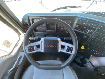Dashboard and steering wheel of a 2019 Mack AN64T70 truck cab interior with Mack logo on center of steering wheel.