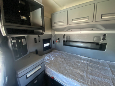Cab interior of a 2019 Mack AN64T70 sleeper truck showing bunk area with overhead storage, side cabinets, and Mack logo on dash area.