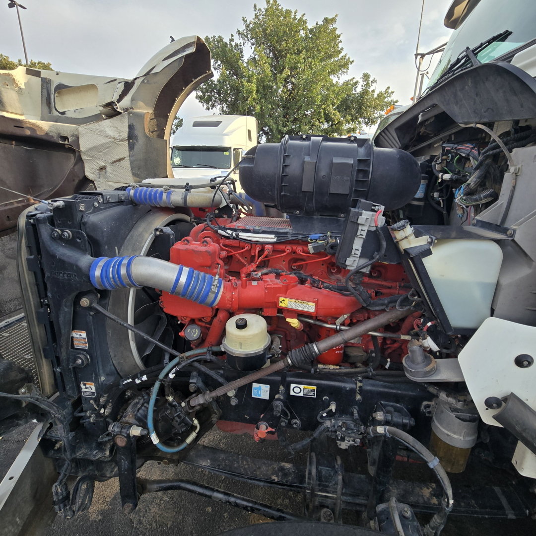 Kenworth T800 engine bay showing red engine, intake, hoses, wiring, and surrounding components.