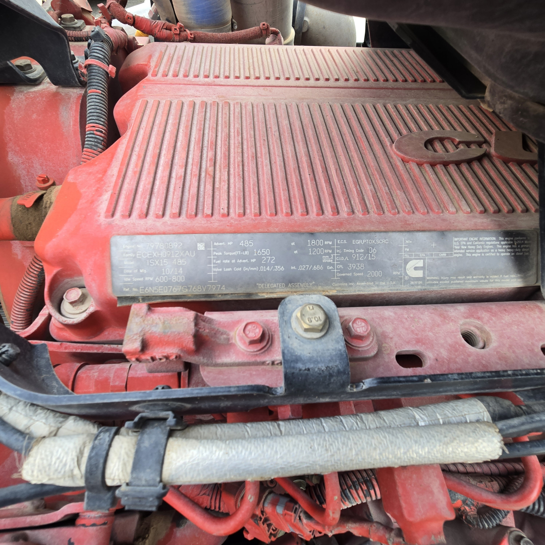Kenworth T800 engine bay showing label with technical specifications on the valve cover and surrounding red components.