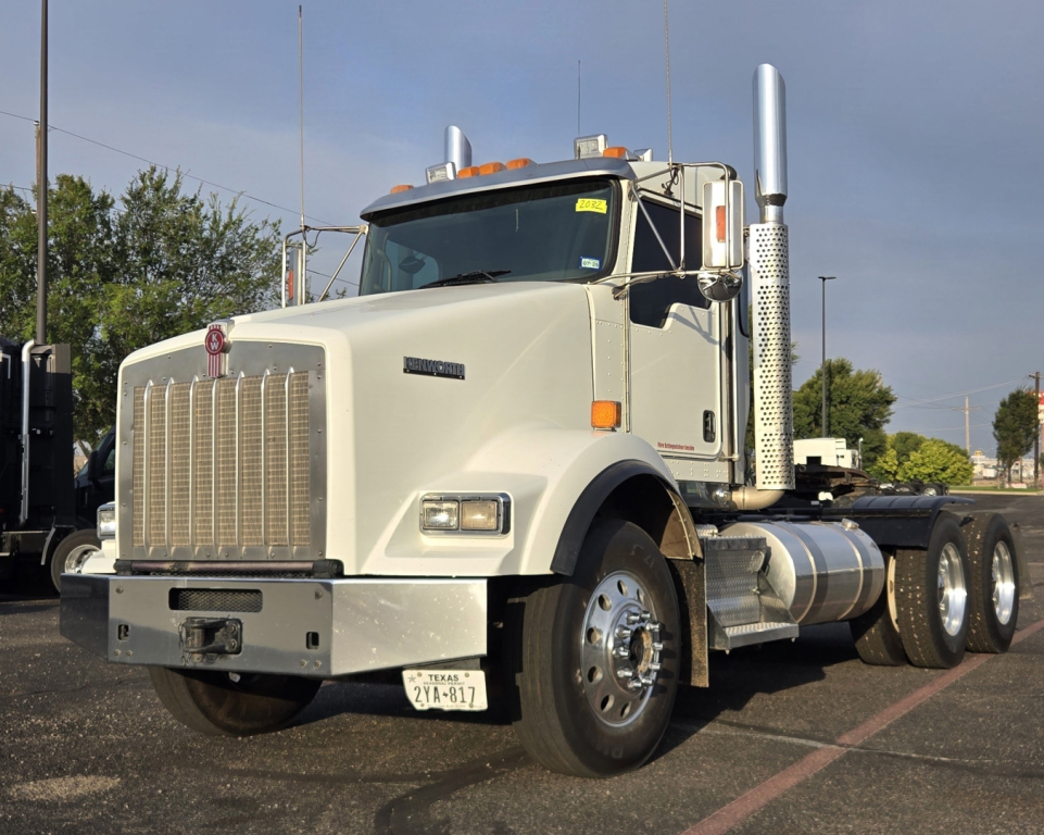 Kenworth T800 truck front-left view showing large chrome grille and dual exhaust stacks.