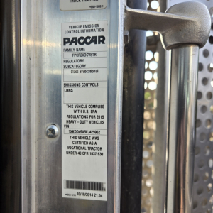 VIN plate on truck door shows vehicle emission controls label from PACCAR and text indicating vocational heavy-duty classification, 2015 Kenworth T800 listing information.