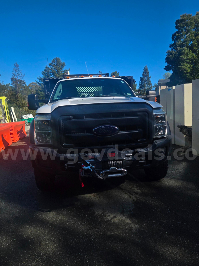 Ford F-450 front view with winch and black grille, showing headlights and bumper, truck in outdoor lot.