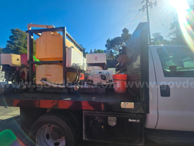 2015 Ford F-450 truck bed showing portable fuel tank, equipment, and tools in the flatbed area.