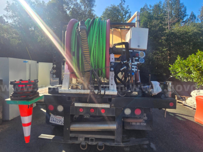 Ford F-450 utility truck rear view showing colorful hoses mounted on hose reel and hydraulic equipment.