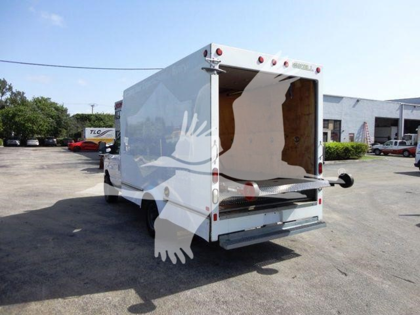 Ford E-350 cargo box rear view showing white box truck with open rear doors and wooden interior, undercarriage and tailgate visible.