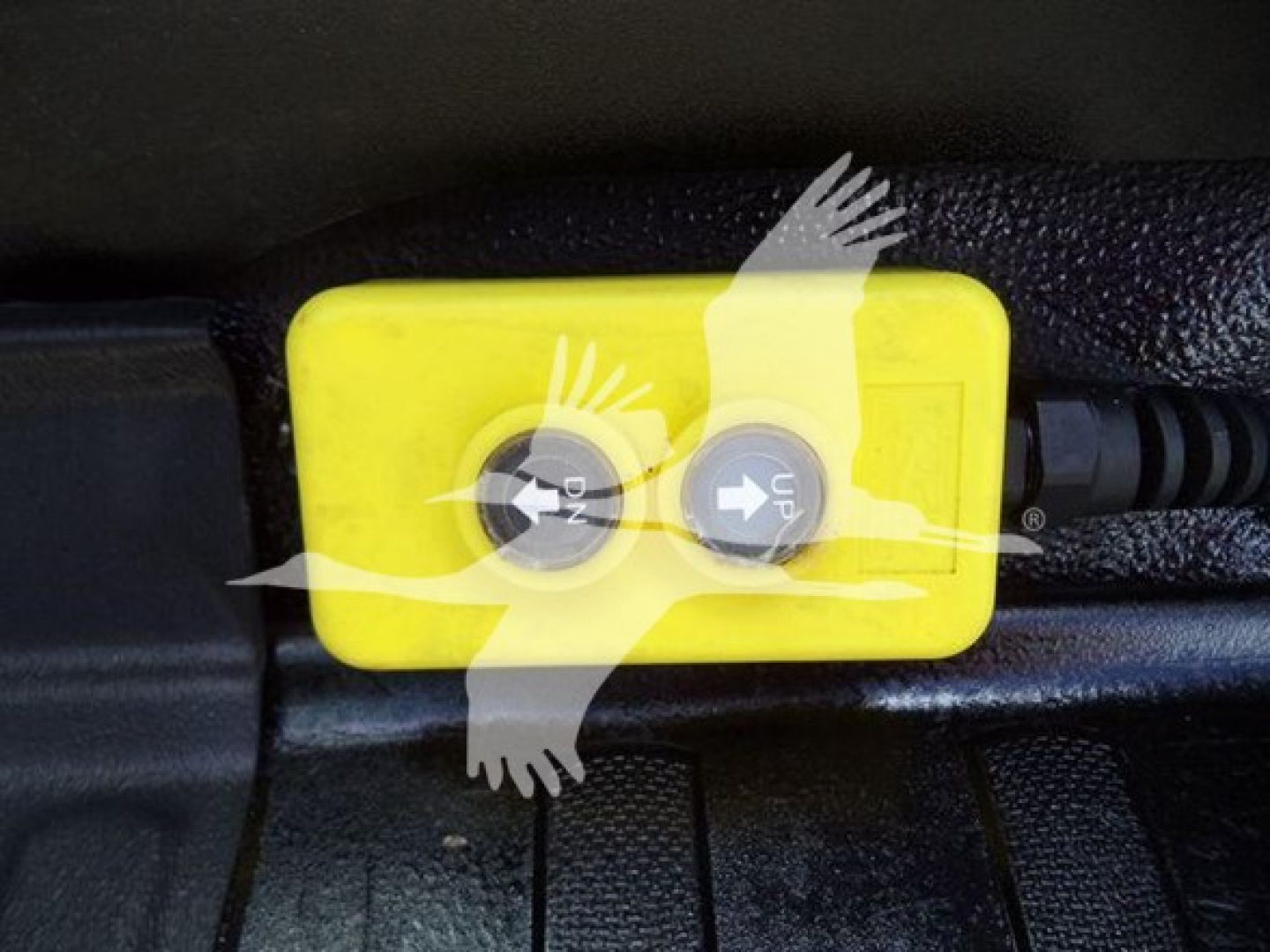 Yellow toggle switch box with two black circular buttons labeled 'ON' and 'UP' in a truck interior floor area.