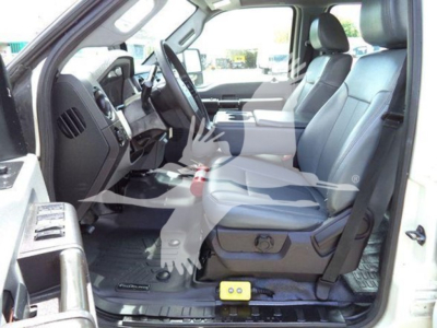 Ford F-550 cab interior front seats and dashboard view with manual controls visible, light gray upholstery, yellow jump box on floor, open driver-side door