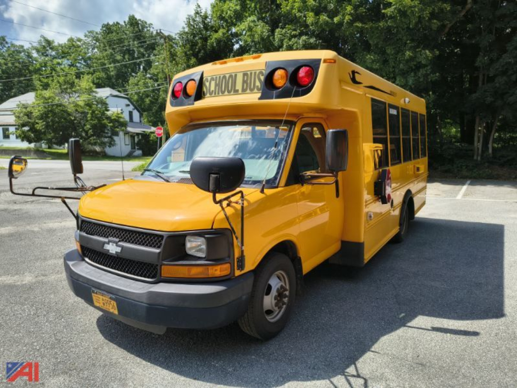 School bus showing Chevrolet Express body with yellow paint and black front grille, side mirrors, and stop-arm area, front view angled.