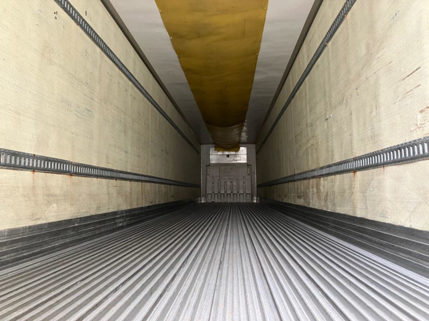 Interior of a 2012 refrigerated trailer with ribbed metal floor and yellow ceiling beam visible at far end.