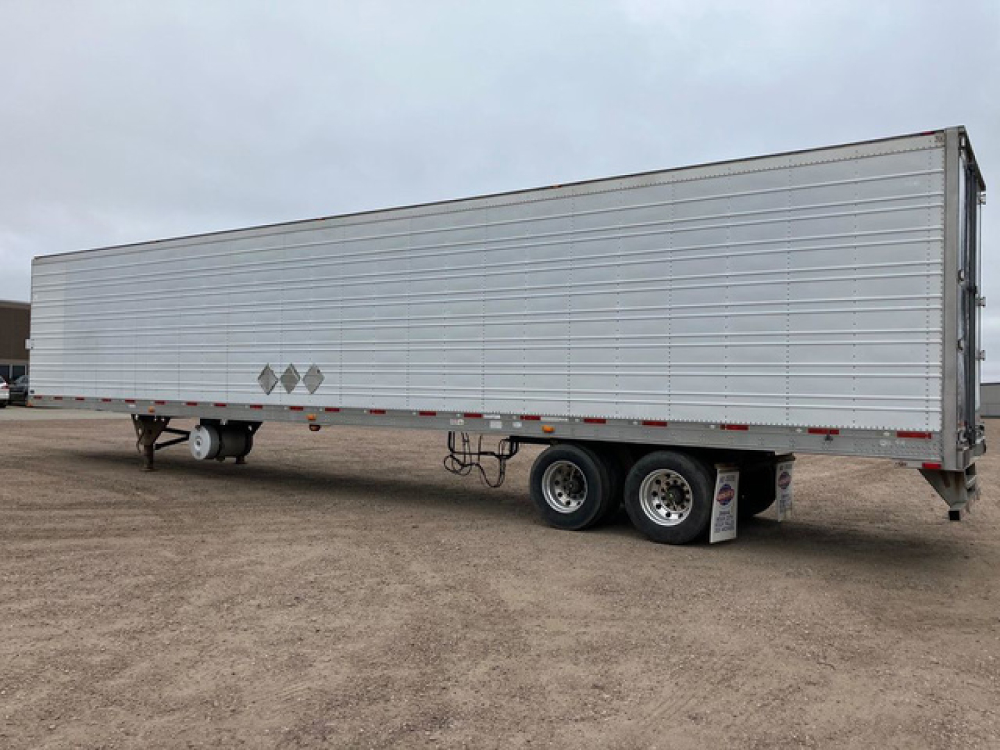 Trailer side view of a 2012 Utility reefer refrigerated trailer with a long aluminum exterior and dual rear axles.