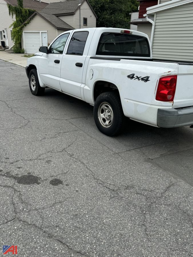White 2006 Dodge Dakota pickup truck 4x4 shown from rear-side angle with bed rails and tail light visible in residential street setting.