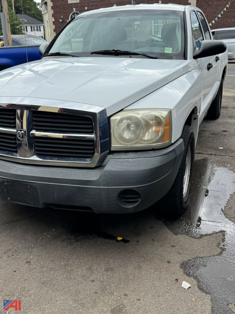 Dodge Dakota pickup truck front-left view showing chrome grille, headlights, and silver body with gray bumper.