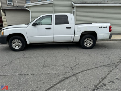 White 2006 Dodge Dakota pickup truck 4x4 shown in side profile with extended cab, dual rear doors, and quad cab style parked on street.