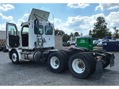 Truck chassis cab of a 2020 Freightliner Cascadia126 with open cab doors, rear dual axles, and exposed wiring; stock area in background.