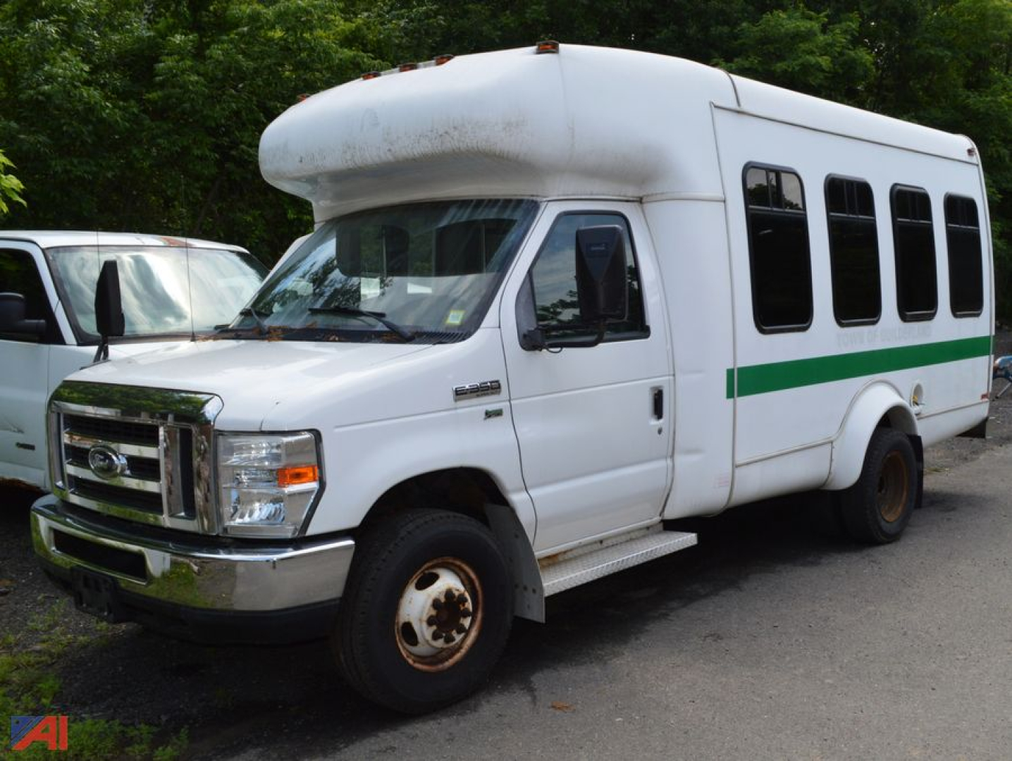 Ford E-350 Super Duty wheelchair bus side view showing green stripe, large front bumper, and wheelchair-accessible body.