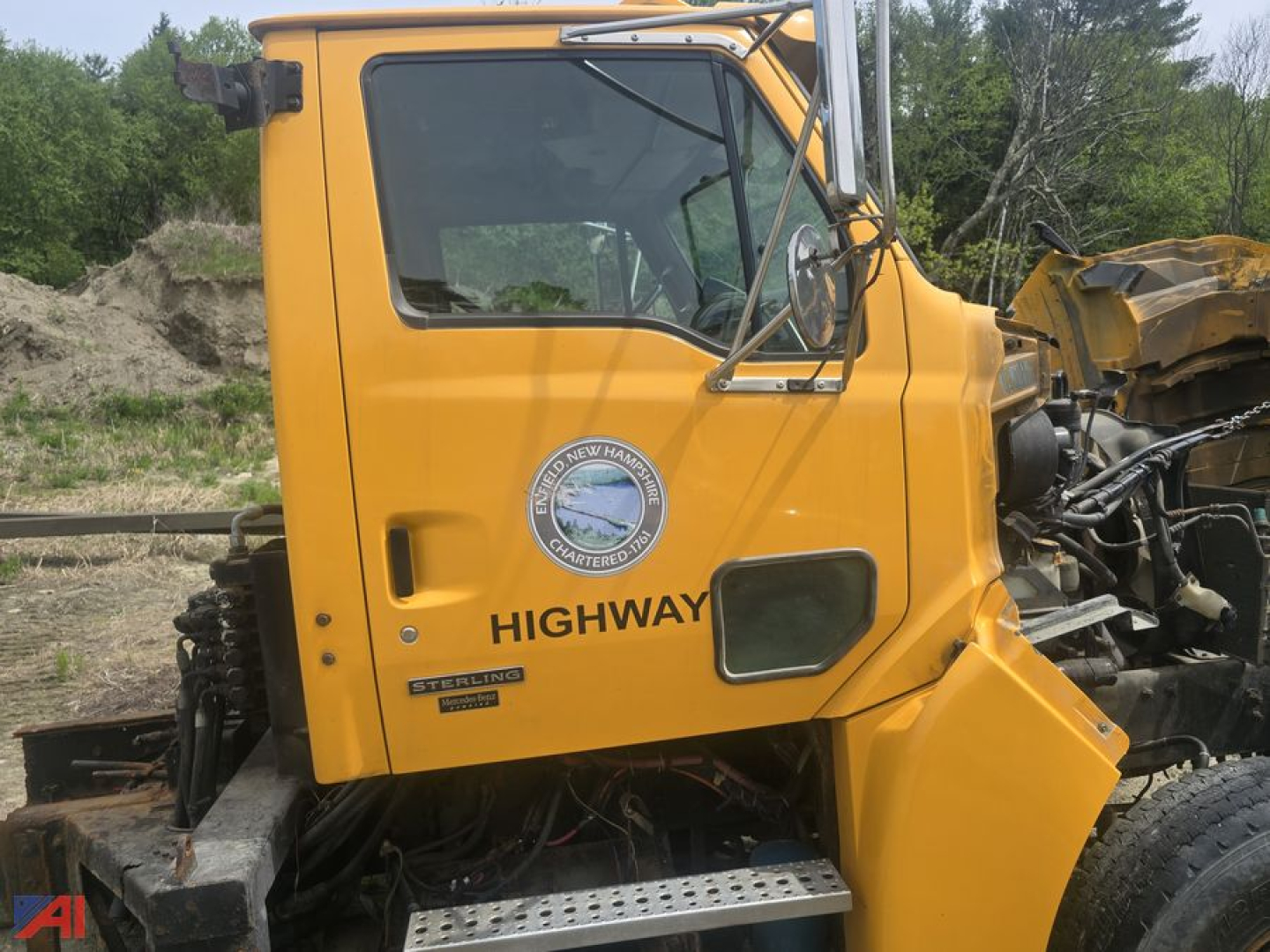 Cab and chassis truck side view showing Sterling Highways emblem and door text, yellow paint, partial engine and chassis components visible