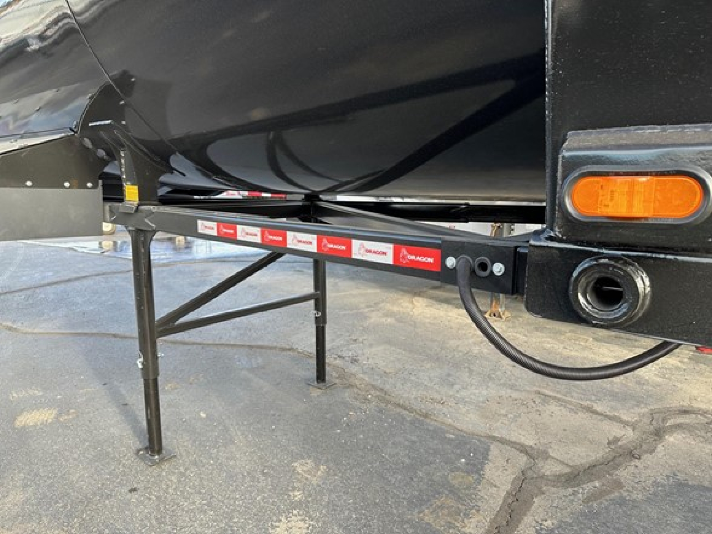 Trailer side view showing support legs and undercarriage with reflective strip and orange marker light.