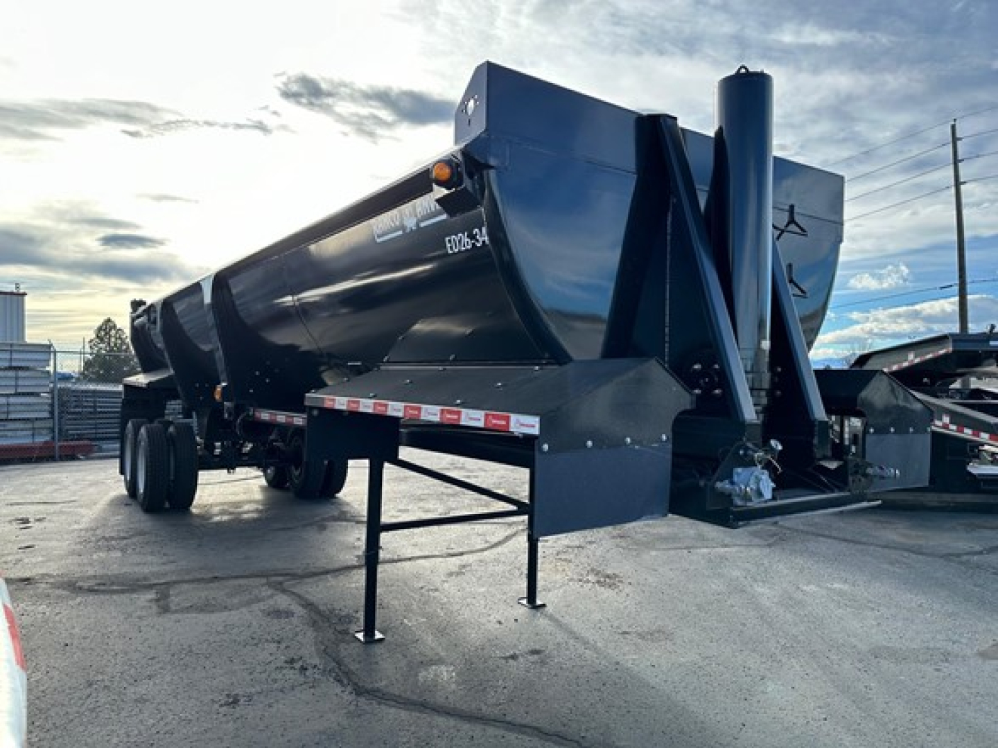 Dump trailer showing ED26-34 model marking, dual axle rear, black painted steel, front landing gear, and tag area with VIN plate visible.