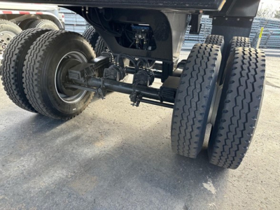 Trailer axle and dual rear wheels showing rear suspension and drive components of a new dump trailer, including axles, leaf springs, and tires.