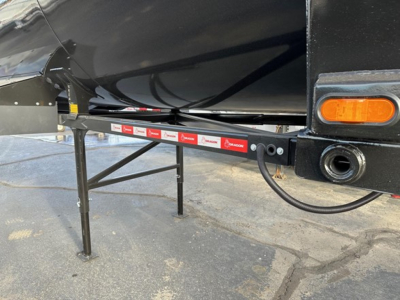 Trailer side view showing support legs and undercarriage with reflective strip and orange marker light.