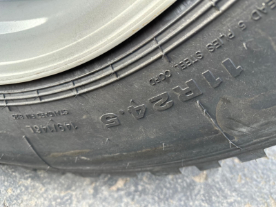 Trailer tire tread close-up with embossed lettering and wheel well visible.