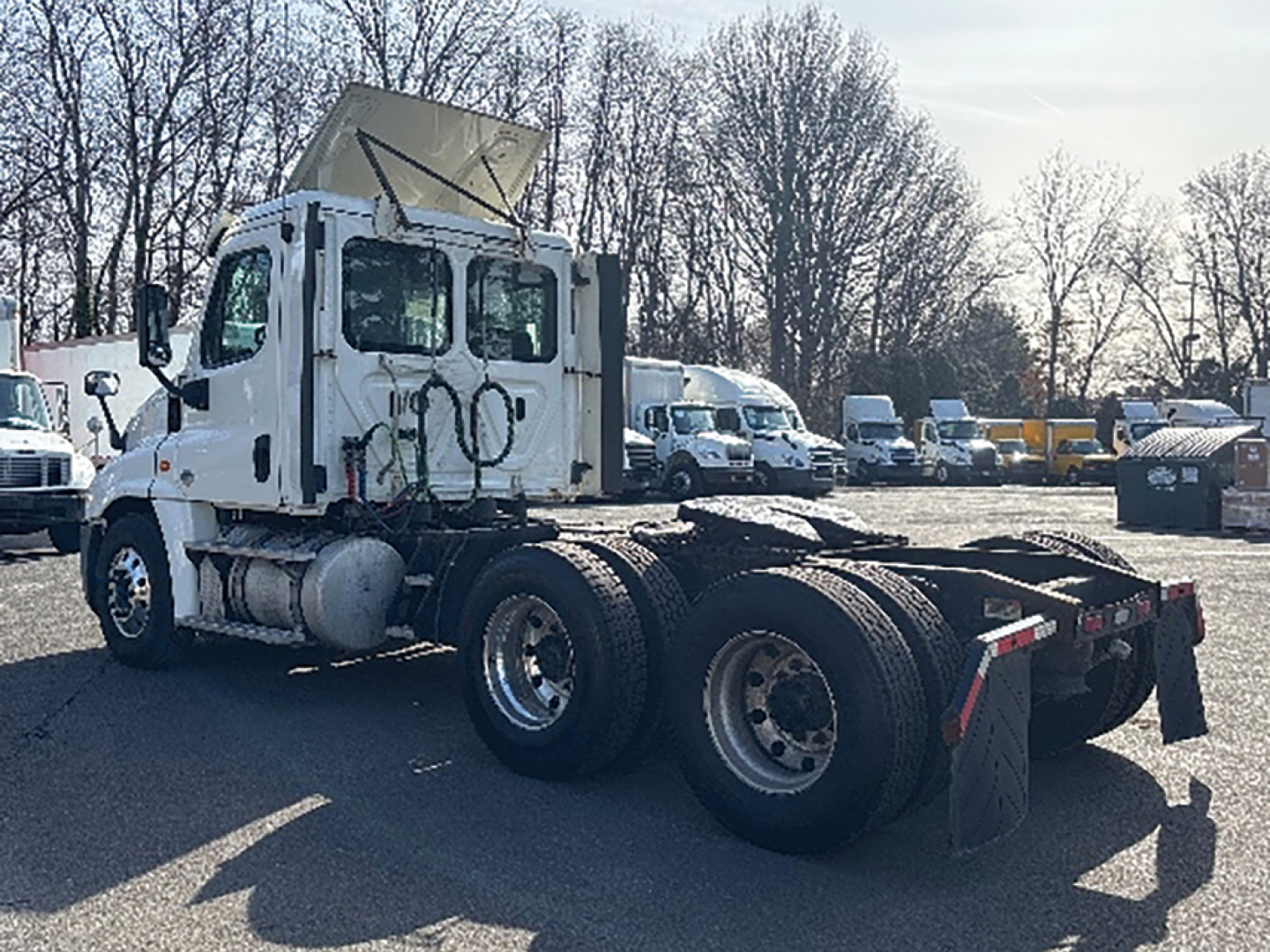 Freightliner Cascadia125 tractor cab with empty flatbed rear, side view showing dual rear axles and fifth wheel, used truck.