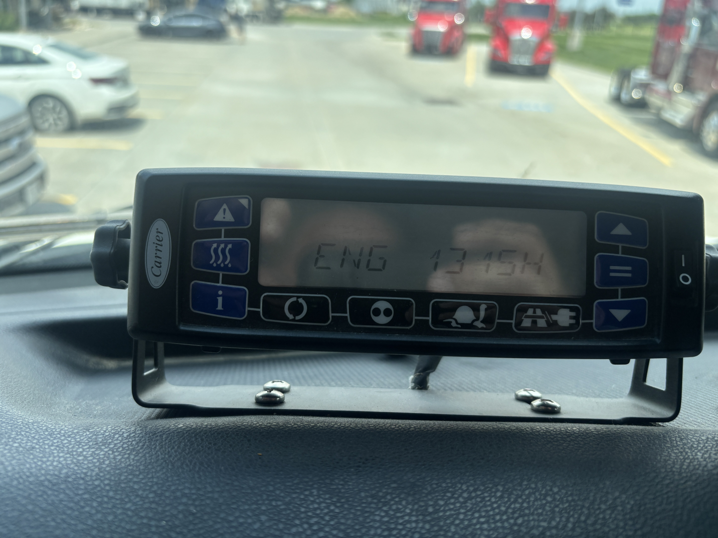 Truck cab dashboard device displaying vehicle information with alphanumeric readout.
