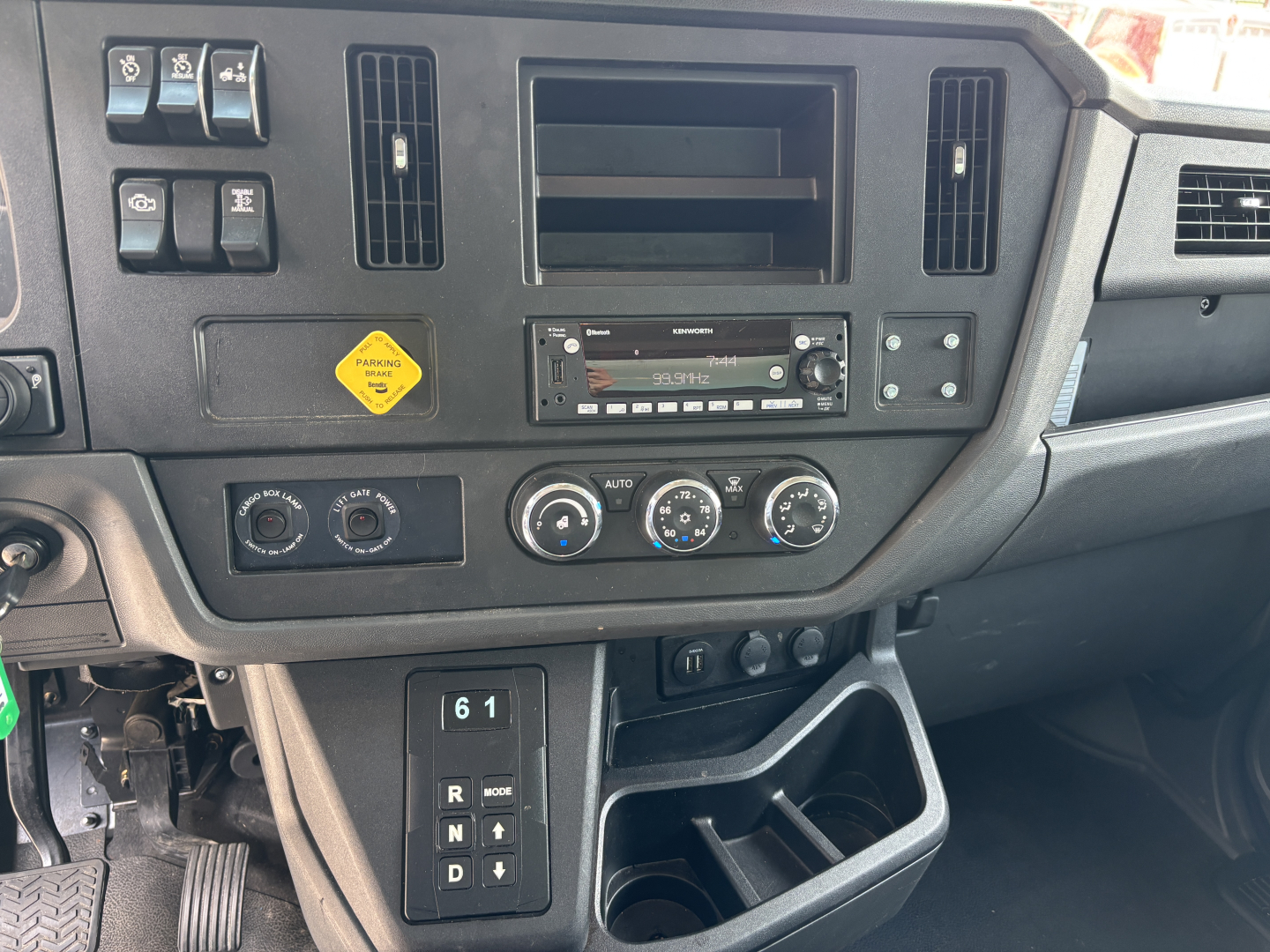 Kenworth T380 cab interior dashboard view showing HVAC controls, radio, ventilation vents, and storage compartments.