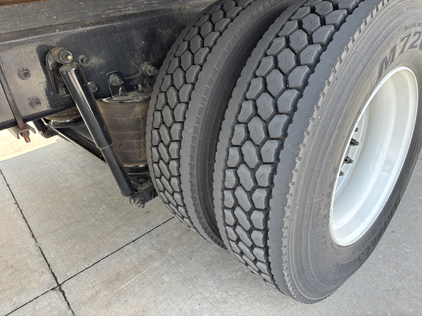 Kenworth T380 rear dual tires and suspension components visible in the wheel area with tire treads and white wheel rims.