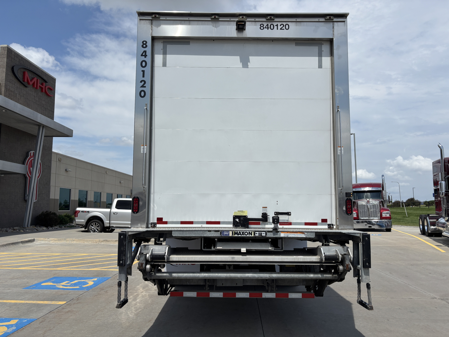 Kenworth T380 refrigerated truck rear view showing liftgate and bumper with reflective tape, VIN/stock number markings not visible on door.