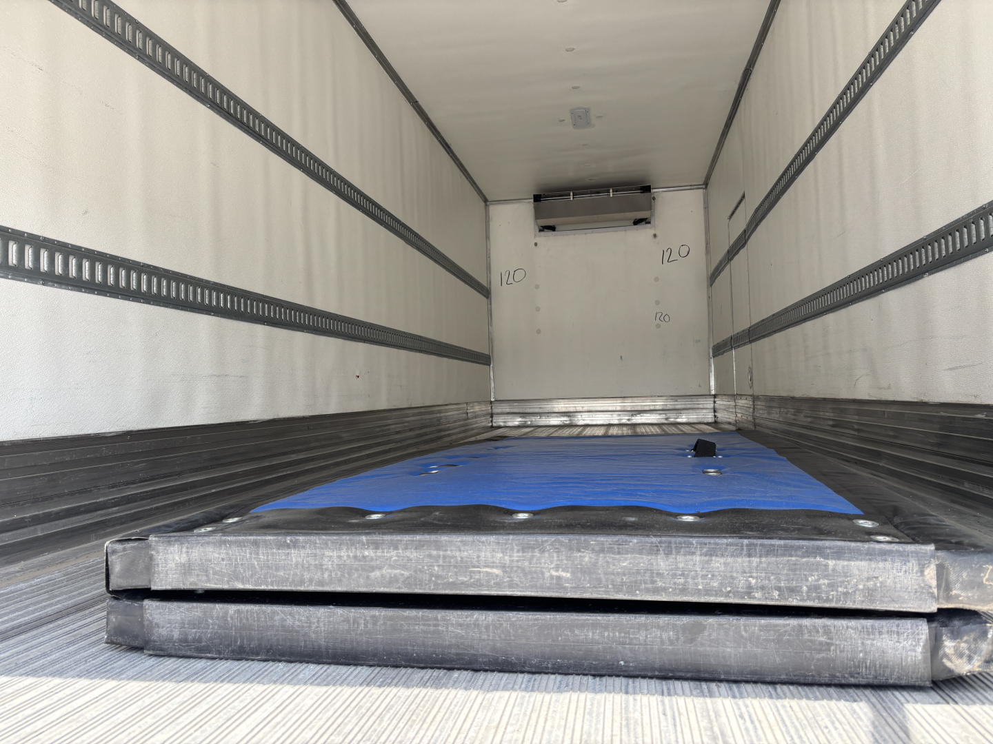 Interior of a Kenworth T380 refrigerated truck trailer showing empty cargo area with a blue tarp and insulated walls.