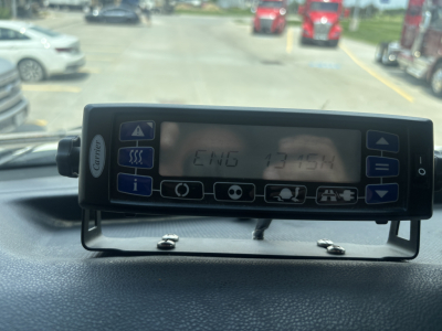Truck cab dashboard device displaying vehicle information with alphanumeric readout.