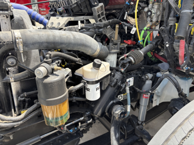 Kenworth T380 engine bay showing fuel filter canister and various hoses and wiring in a refrigerated truck.