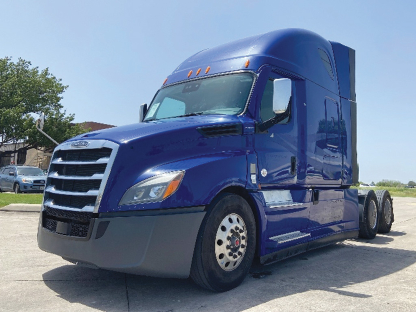 Blue Freightliner Cascadia126 tractor-trailer cab side view showing front grille, wheel, and sleeper cab.