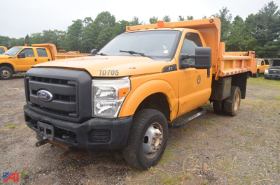 Ford F-350 Super Duty dump truck in orange, front-left view, TD705 badge on hood and dump bed visible, black grille, roadside lot.