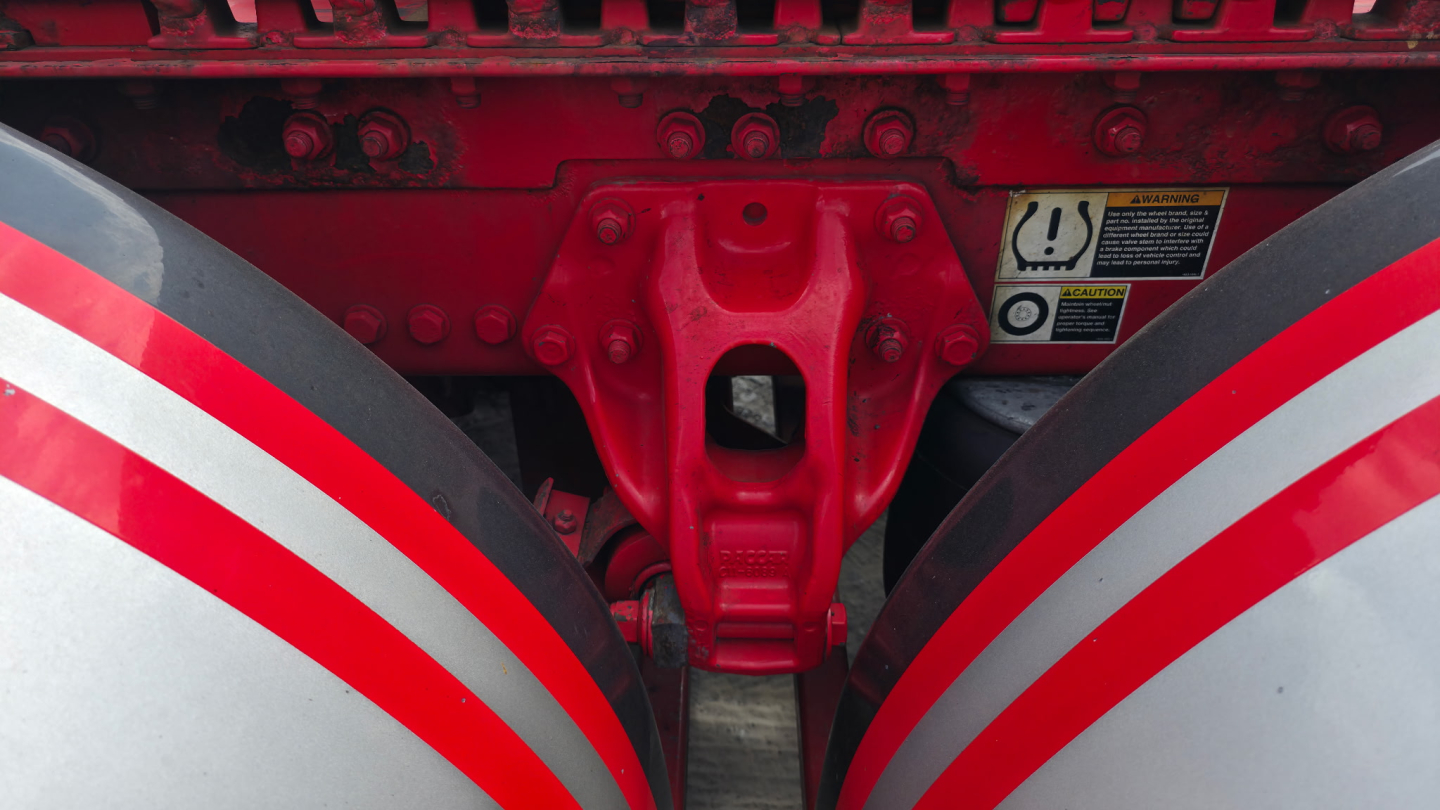 Kenworth truck chassis center view showing red hitch and dual red frame with warning sticker