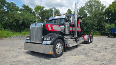 Kenworth W900L sleeper tractor with chrome grille, black and red paint, dual exhaust stacks, and dual rear axles.