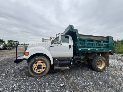 Ford F-750 dump truck side view showing white cab and green dump bed with black chassis and large rear wheels.