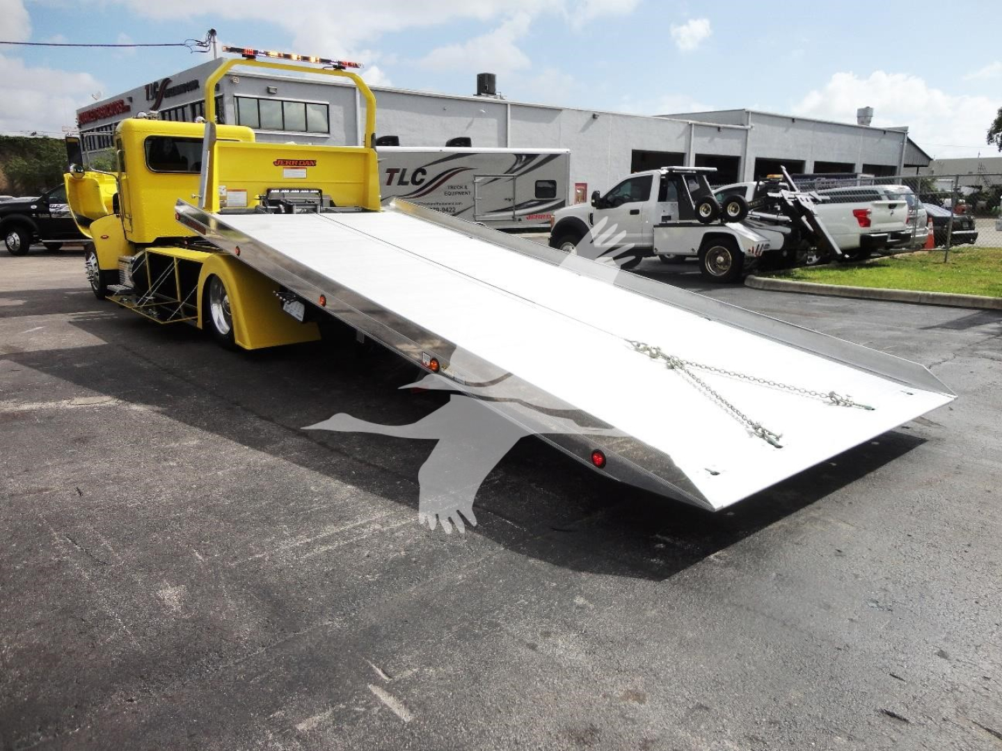 Peterbilt 337 rollback tow truck with a raised aluminum ramp in a parking lot.