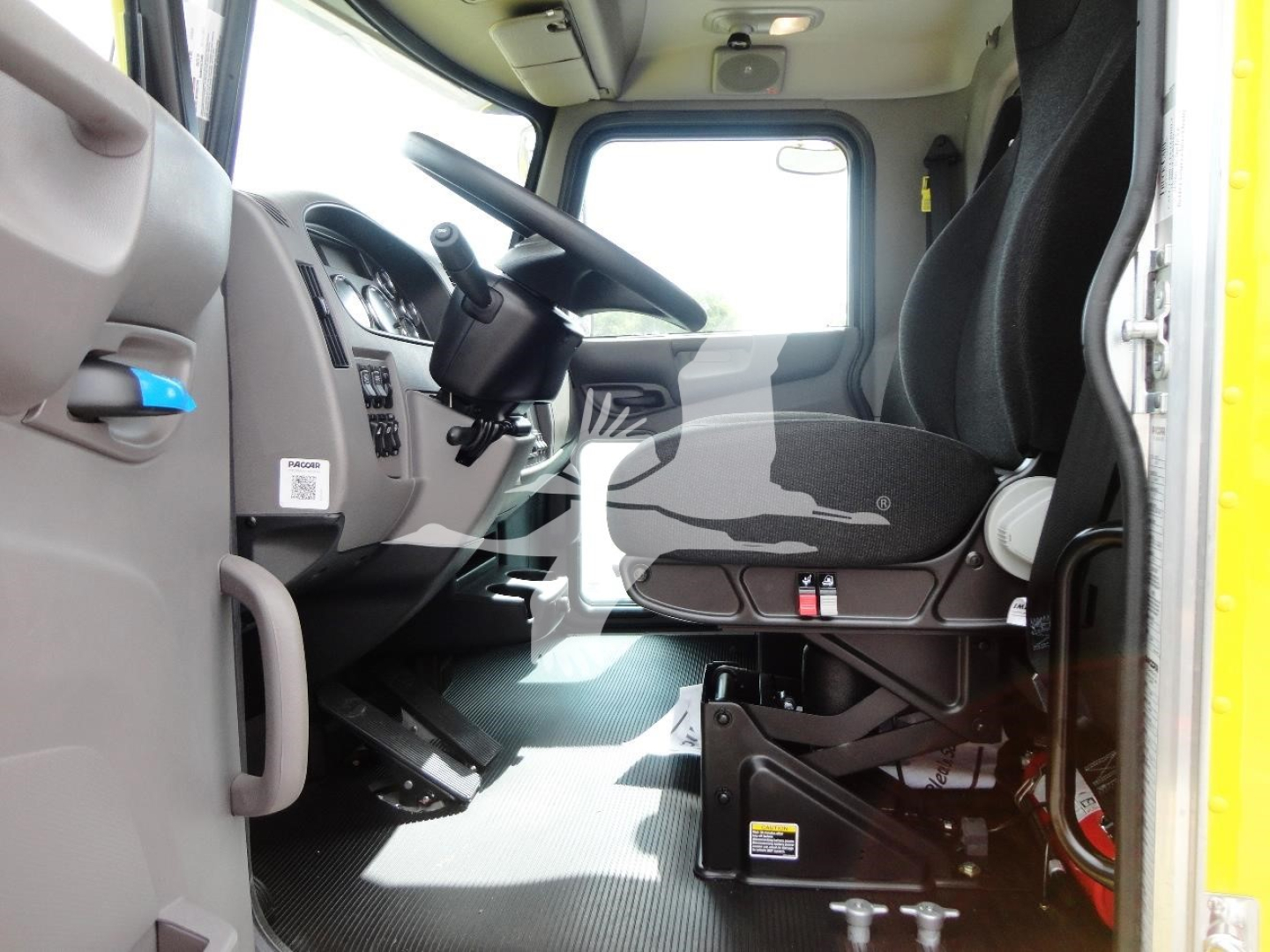 Peterbilt 337 cab interior showing driver seat, steering wheel, and dashboard in a clean new truck.