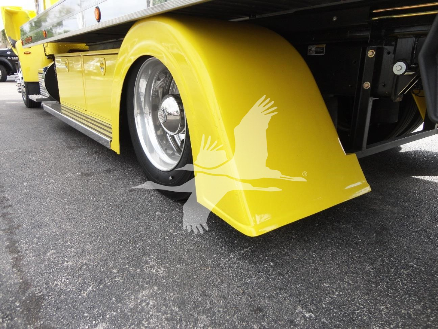 Peterbilt 337 rollback truck side view with yellow front fender mudflap and chrome wheel; wheel well and running board visible.