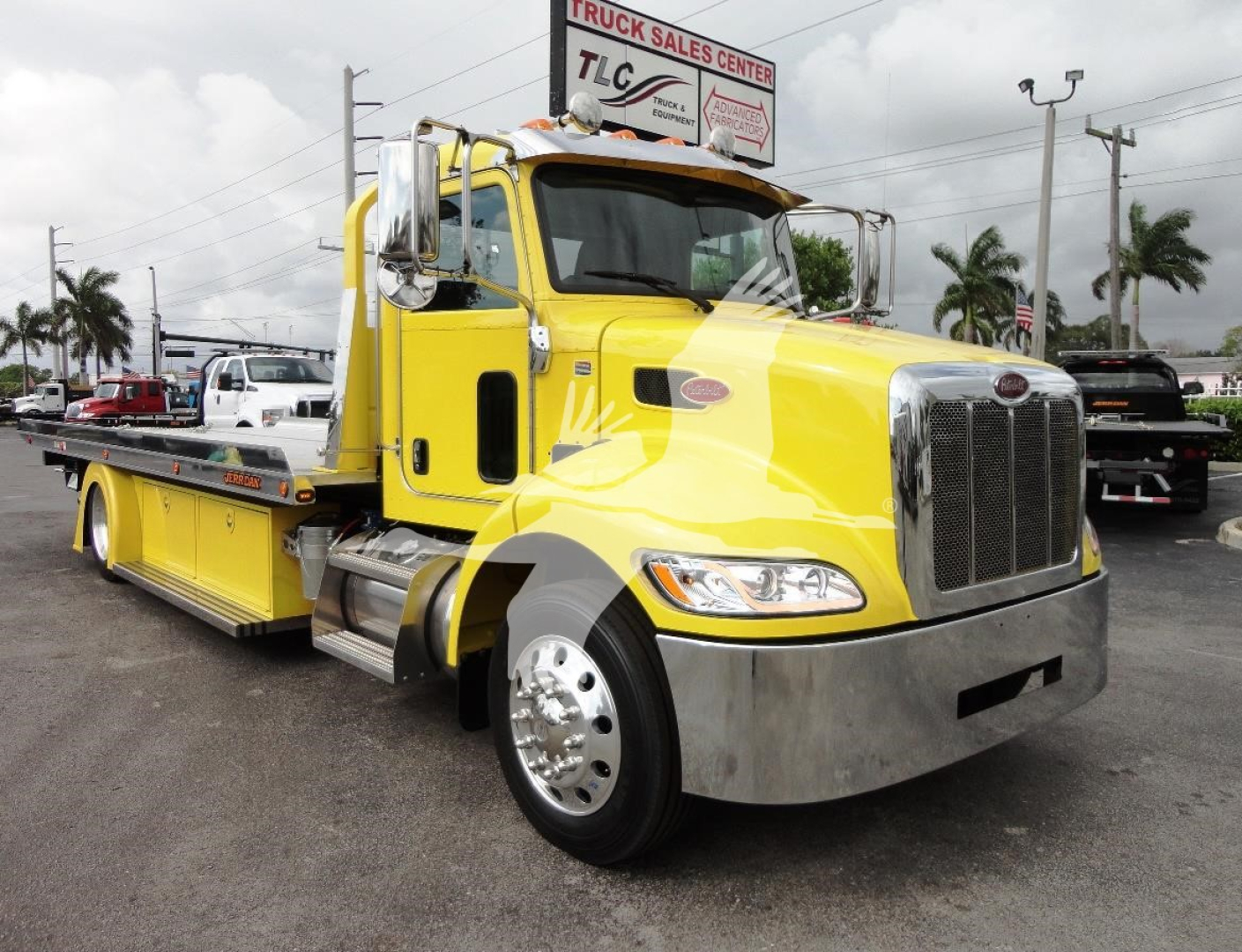 Yellow Peterbilt 337 rollback tow truck side view showing chrome grille and flatbed with wheel accents.