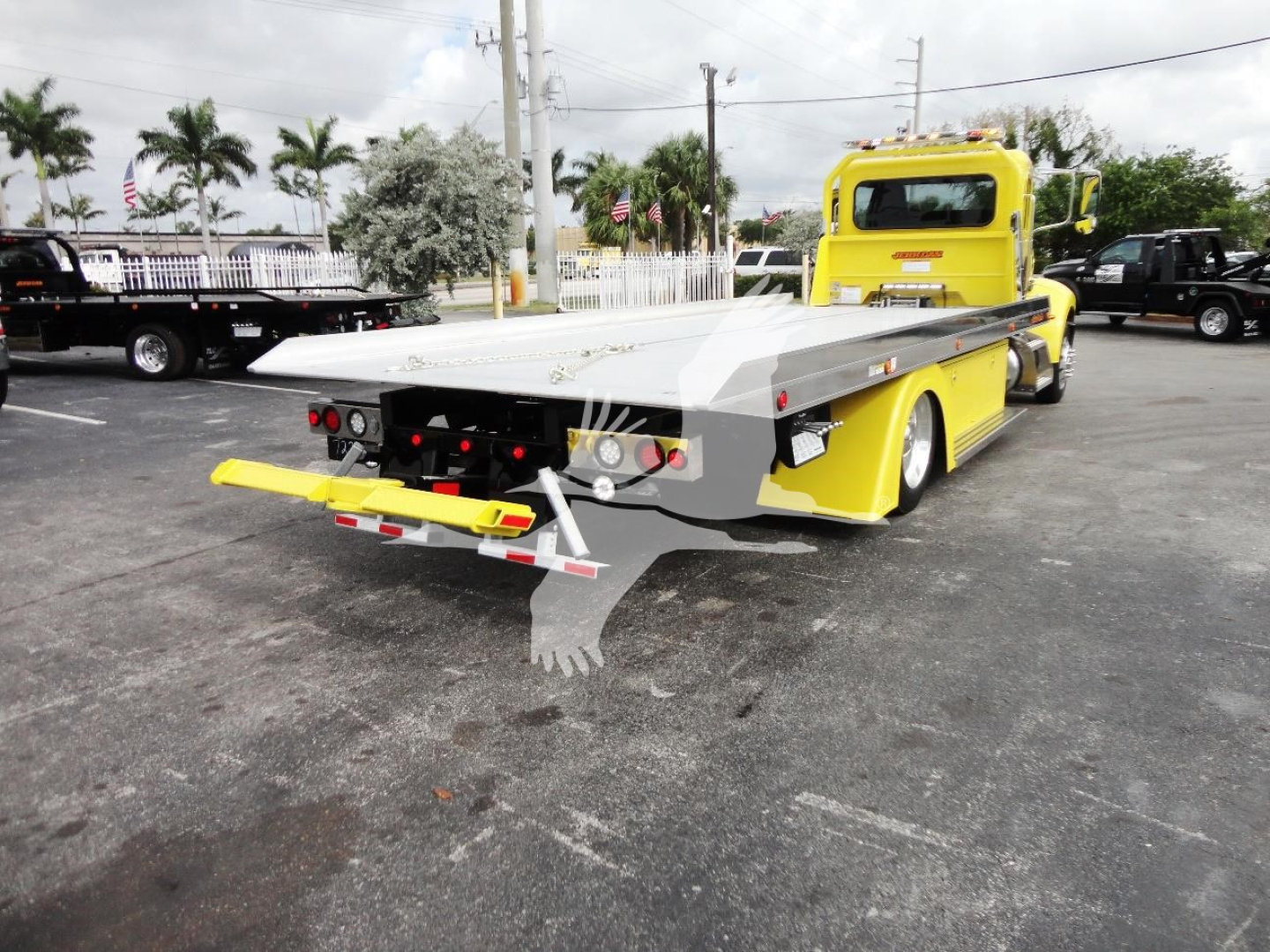 Peterbilt 337 rollback tow truck in yellow with flatbed rear, viewed from rear-left angle.