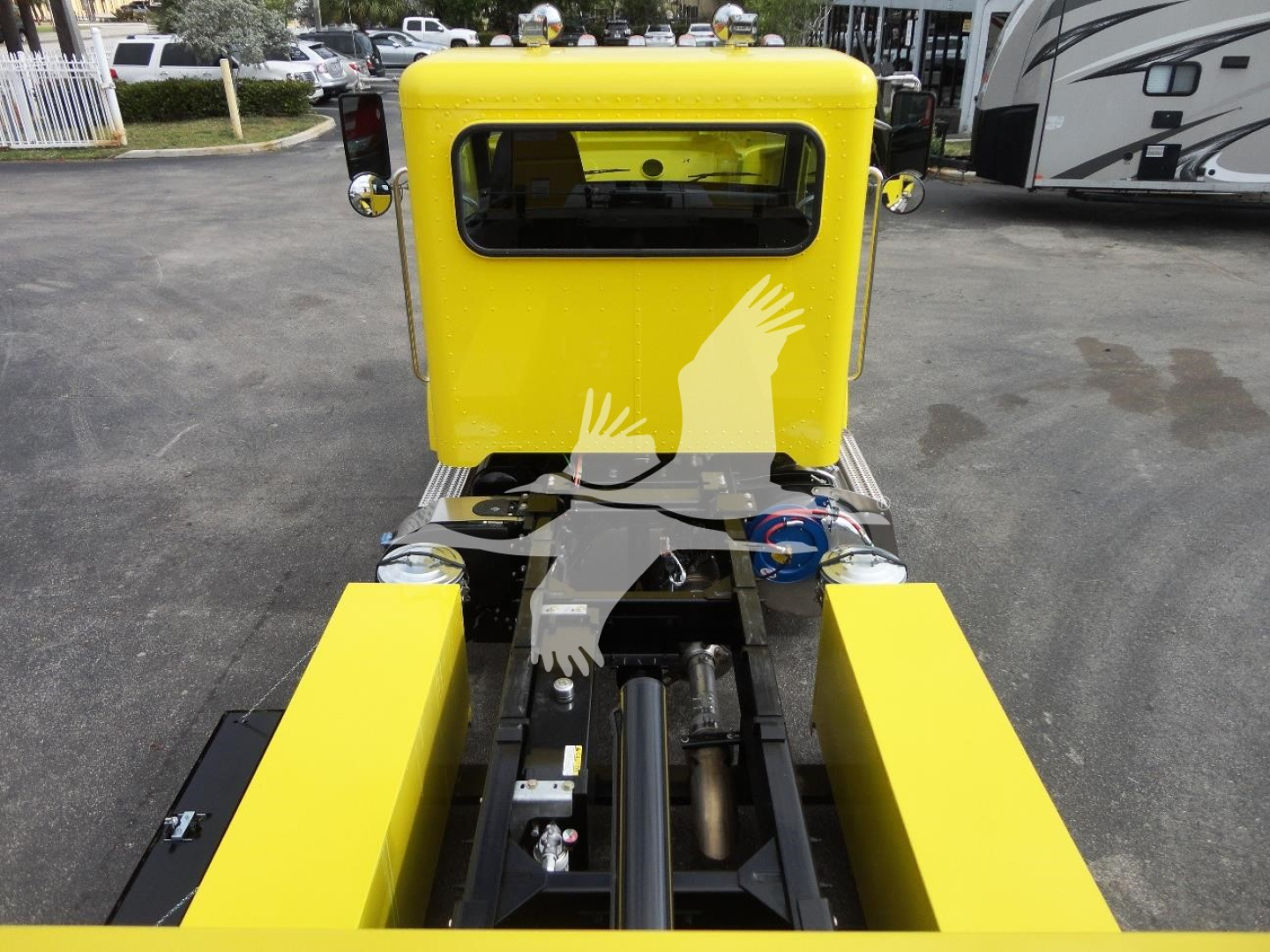 Yellow Peterbilt 337 rollback truck chassis with hydraulic rams and control levers visible, rear view showing bright yellow cab and frame, stock number J56560.
