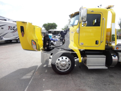 Peterbilt 337 truck cab in yellow with rollback bed deployed, front wheel visible, side steps, and exposed engine area.